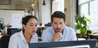 Two office workers at a shared desk look alarmed
