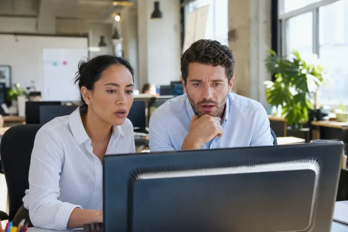 Two office workers at a shared desk look alarmed Two office workers at a shared desk look alarmed