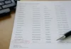 Close-up of a printed report with agent names and access scopes, a pen resting on the page, softly defocused text.