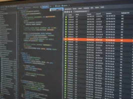 North Korea Runs Cloud Supply Chain Attacks Through the Blockchain, Unit 42 Finds A close-up of a computer monitor displaying a code editor and a connection-monitoring panel with outbound data.