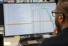 Software Supply Chain Security Miss Drained $3M from Polymarket A person with glasses views a brightly lit code editor displaying a JavaScript dependency list, with one entry highlighted in amber.