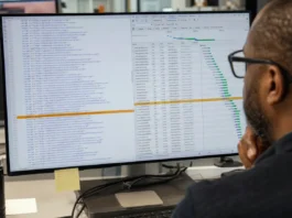 A person with glasses views a brightly lit code editor displaying a JavaScript dependency