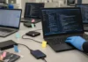 Authorities Dismantle AudiA6, the Ransomware Crypto Laundering Service Behind $380M A brightly lit table displays several laptops and external hard drives, each tagged with color-coded adhesive markers.