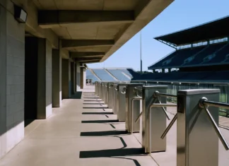 Ajax Cyber Breach Exposed 300,000 Fan Records and Stadium-Ban Controls Empty stadium concourse in bright daylight, featuring turnstile barriers and a view of the stands, shot from ground level.