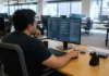 Shadow AI Is a Concentration Problem, and Broad Policy Misses It A focused employee at a workstation in a bright, open-plan office, using an AI chat application on a monitor.