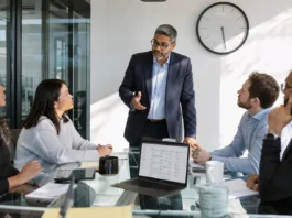 The Biggest CISO Challenges of 2026: 73% Still Aren’t Ready for a Major Attack A CISO in business attire stands at a glass conference table, discussing with colleagues around a laptop and clock on the wall.