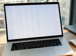 A close-up of a MacBook Pro on a clean desk, displaying a spreadsheet