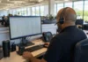 How Stale Credentials Drove the Worst Data Breach Incidents of 2026 A technician with a headset sits at a workstation, facing a computer screen in a bright office environment.
