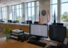 Bright, sunlit interior of a modern public-records office with a long service counter, unoccupied desks, and official flags.