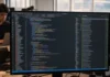 OpenAI Daybreak Shifts AI Security Focus from Finding to Fixing A brightly lit monitor displays a dark-themed code editor filled with colorful code, set in a modern office environment.