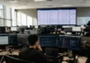 Unit 42: 72-Minute Breach Exposes SOC Detection Response Time Gap Brightly lit SOC operations floor with multiple monitors, showing a cloud monitoring console, viewed from the back of the room.