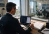 A Quarter of CISOs Considered Quitting as AI Governance Landed on Them A CISO-level executive in business attire sits at a desk, reviewing a laptop