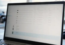 Helpdesk Impersonation: The Four Post-MFA Stages CISOs Need to Detect A laptop monitor displays a brightly lit authentication management console with a list of identity provider devices.