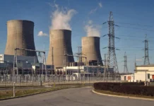 Origin Energy Sector Data Breach Widens to 5 Million Customers A large electrical power station seen from outside, with cooling towers and a high-voltage substation switchyard under a clear sky.