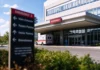 Craneware Healthcare Data Breach Puts 2,000 Hospitals at Risk Exterior of a modern hospital with a covered emergency entrance and an ambulance at the ambulance bay in daylight.