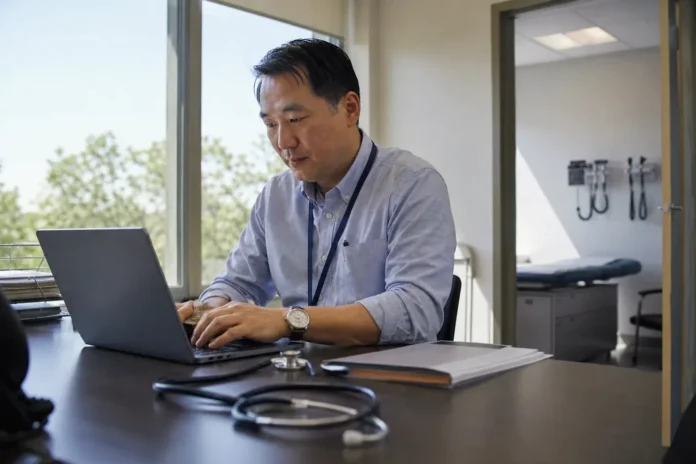 Clinic administrator working at a laptop in a bright medical office Clinic administrator working at a laptop in a bright medical office